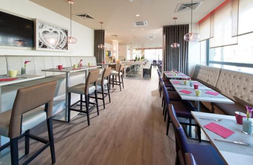 a restaurant with a row of tables and chairs at Leonardo Hotel Munich City Olympiapark in Munich