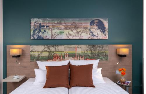 a bedroom with a bed with a painting above it at Leonardo Hotel Munich City Olympiapark in Munich