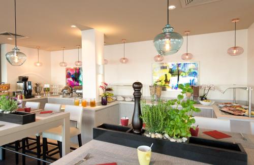 a dining room with tables and chairs and pendant lights at Leonardo Hotel Munich City Olympiapark in Munich