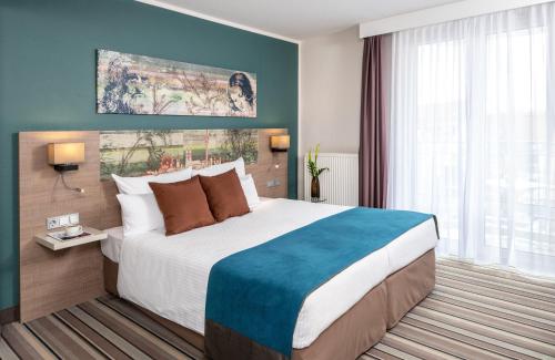 a bedroom with a large bed and a large window at Leonardo Hotel Munich City Olympiapark in Munich