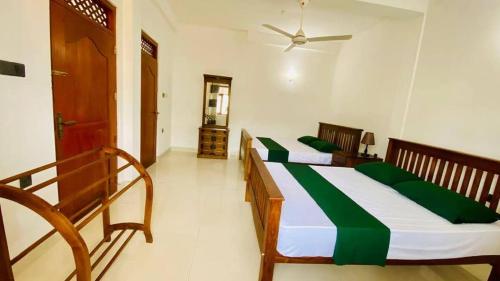 a bedroom with two beds with green sheets at Jasmine Apartments in Negombo