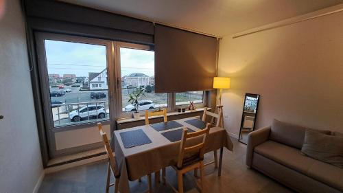 a dining room with a table and a couch and a window at studio la petite sirene in Middelkerke