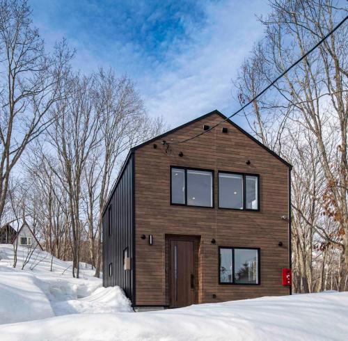 a wooden house in the snow with trees at 豆の家Beanz House in Niseko