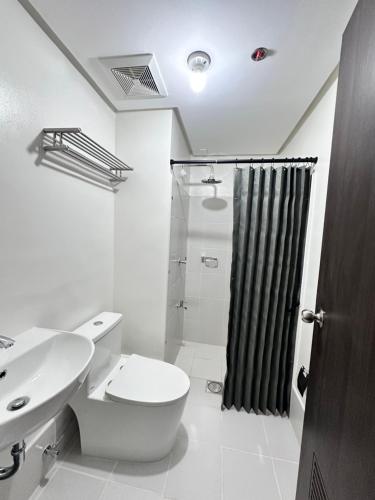 a bathroom with a toilet and a sink and a shower at Covent Garden Condominium in Manila