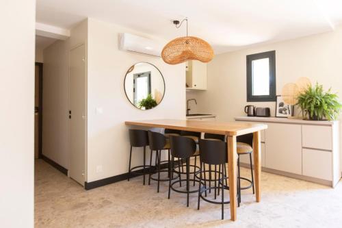 a kitchen with a wooden table and bar stools at Les Villas du Château de Lastours in Portel-des-Corbières