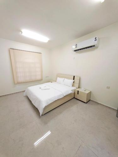 a bedroom with a white bed and a white wall at Nizwa Diamond ماسة نزوى in Nizwa