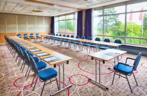 a row of tables and chairs in a room with windows at Leonardo Hotel Heidelberg Walldorf in Walldorf