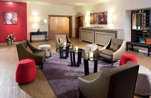 a lobby with chairs and tables and a fireplace at Leonardo Hotel Heidelberg Walldorf in Walldorf