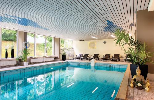 an indoor swimming pool with a blue tile ceiling at Leonardo Hotel Heidelberg Walldorf in Walldorf
