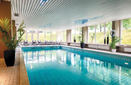 a large swimming pool in a building with windows at Leonardo Hotel Heidelberg Walldorf in Walldorf