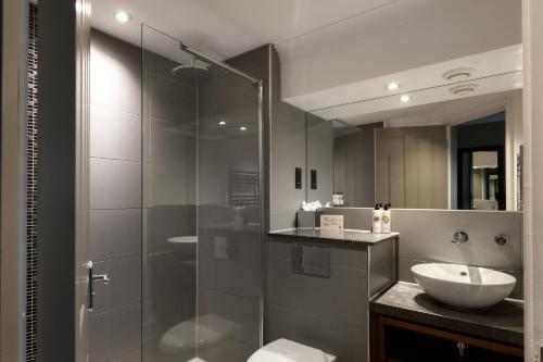 a bathroom with a glass shower and a sink at Rose And Crown Hotel in London