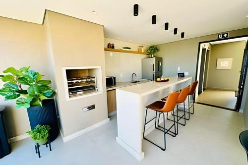 a kitchen with a counter and some orange chairs at Loft Skyline - Vista de tirar o fôlego para cidade! in Uberlândia