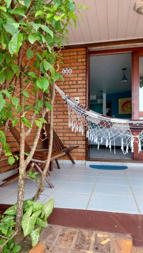 a hammock in front of a building with a tree at Pousada Palmeiras Bombinhas in Bombinhas