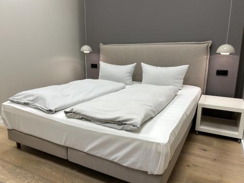 a large white bed with white sheets and pillows at Iderhoff Lounge 01 in Norderney