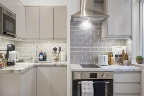 a kitchen with white appliances and white cabinets at Central Harrow 5 Studio Apartment Block in Harrow