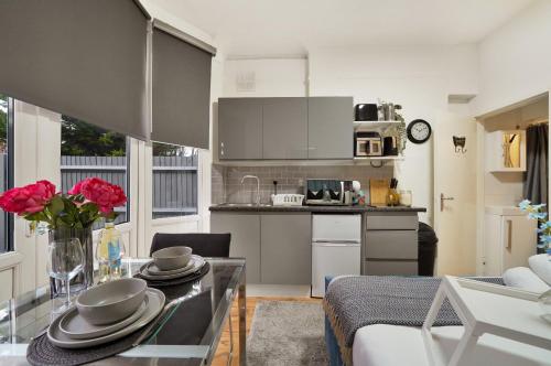 a kitchen and living room with a table with dishes on it at Central Harrow 5 Studio Apartment Block in Harrow