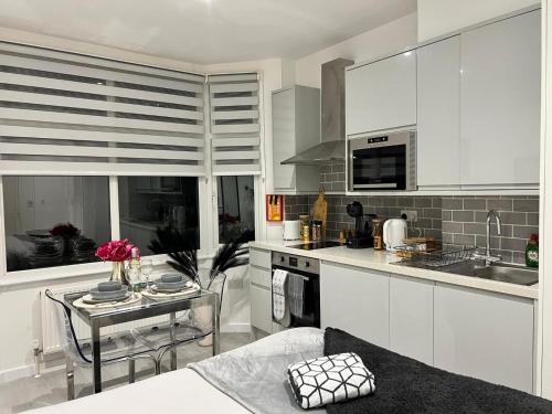 a kitchen with white cabinets and a table with a table at Central Harrow 5 Studio Apartment Block in Harrow
