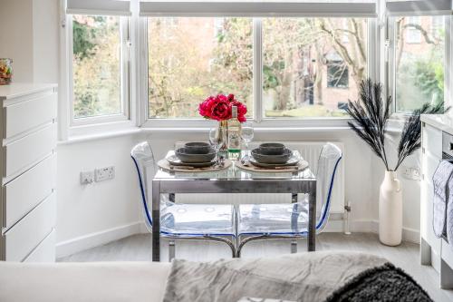 a dining room table with a vase of flowers on it at Central Harrow 5 Studio Apartment Block in Harrow
