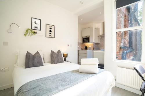 a white bedroom with a bed and a window at Central Harrow 5 Studio Apartment Block in Harrow