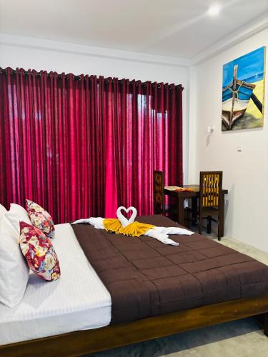 a bedroom with a bed in front of a red curtain at Revival Beach Resort in Hikkaduwa