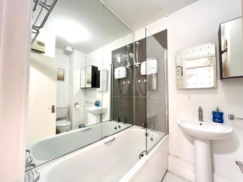 a white bathroom with a tub and a sink at One Bedroom Site Apartment in Dublin