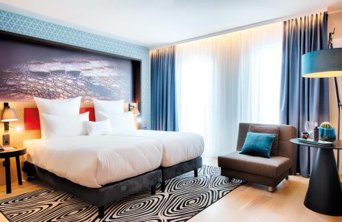 a hotel room with a bed and a chair at NYX Hotel Munich by Leonardo Hotels in Munich