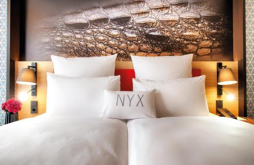 a bed with white pillows in a hotel room at NYX Hotel Munich by Leonardo Hotels in Munich