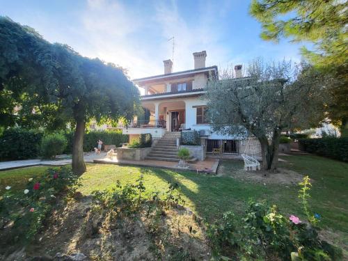 a large white house with trees and a yard at Villa Sophia in Calcinelli