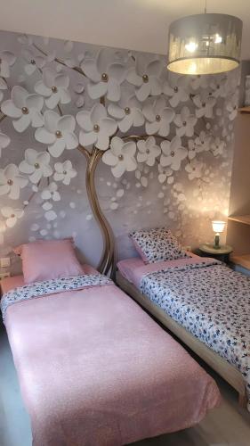 two beds in a room with a tree on the wall at Maison Tiny Bwa in Saint-Cernin-de-lʼHerm