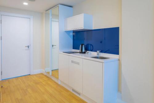 a kitchen with white cabinets and blue walls at Panorama Sea Side Hotel in Batumi