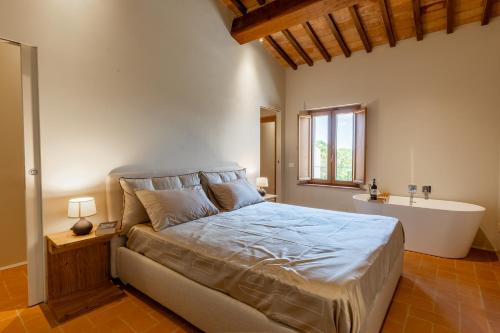 a bedroom with a large bed and a bath tub at Il Colle Verde in Buonconvento
