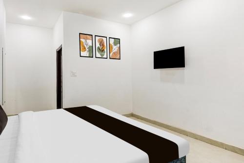 a white room with a bed and three pictures on the wall at Hotel O A-1 Stays in Faridabad