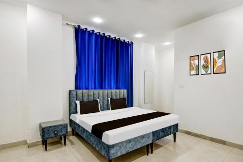 a bedroom with a bed with a blue curtain at Hotel O A-1 Stays in Faridabad