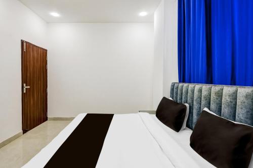 a bedroom with a bed and blue curtains at Hotel O A-1 Stays in Faridabad