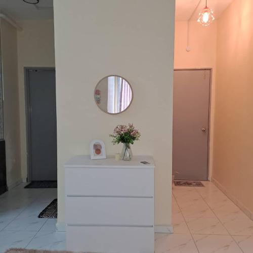 a table with a mirror and a vase of flowers on it at Triple H Homestay in Jitra