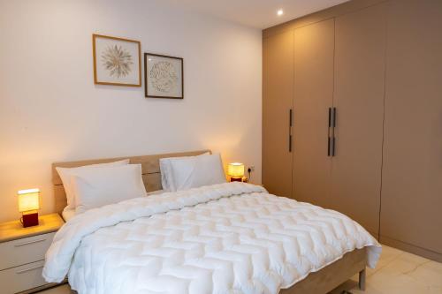 a bedroom with a large white bed and two lamps at Stylish Apartment with Modern Amenities in Nova Roman Ridge in Accra
