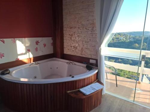 a large tub in a room with a large window at Pousada Casa Pinha em Campos do Jordão in Campos do Jordão