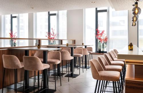 a row of stools in a restaurant with windows at Leonardo Hotel Dresden Altstadt in Dresden