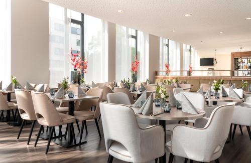 a dining room with tables and chairs and windows at Leonardo Hotel Dresden Altstadt in Dresden