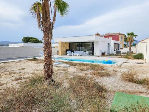 a palm tree in front of a house with a swimming pool at Fee4me Exclusive Villa with Pool and Parking in Mutxamel