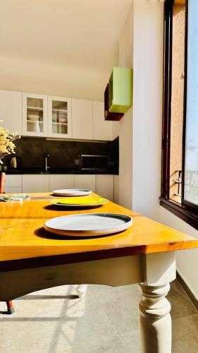 a kitchen with a wooden table with plates on it at La Luna Luz 1BR Apt w Balcony by the Bahsa Sea in Batroûn