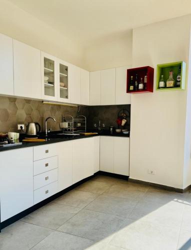a large white kitchen with white cabinets and appliances at La Luna Luz 1BR Apt w Balcony by the Bahsa Sea in Batroûn