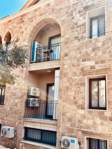 a brick building with an arched window and a balcony at La Luna Luz 1BR Apt w Balcony by the Bahsa Sea in Batroûn