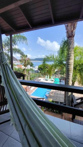 a hammock on a balcony with a view of the ocean at Pousada Palmeiras Bombinhas in Bombinhas