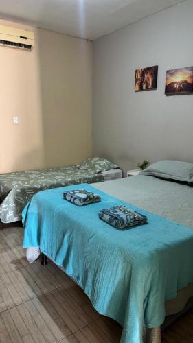a bedroom with two beds and a blue bedspread at Casa Mobiliada com 4 camas e 2 quartos in Juazeiro do Norte