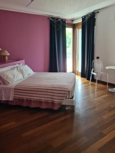 a bedroom with a bed with purple walls and wooden floors at il Sorriso di Angelina in Pescara