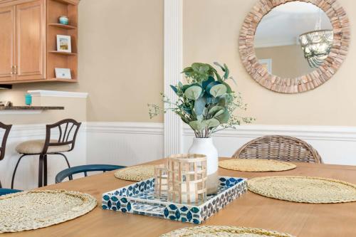 a dining room table with a vase of flowers and a mirror at Brass Rail 315 in Tybee Island