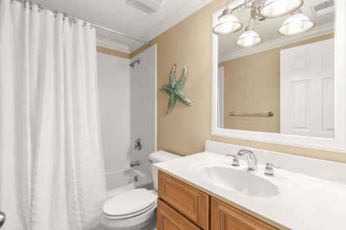 a bathroom with a sink and a toilet and a mirror at Brass Rail 315 in Tybee Island