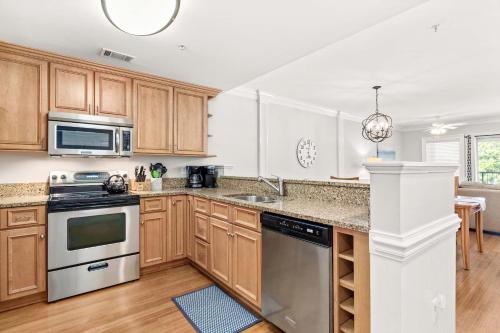 a kitchen with wooden cabinets and stainless steel appliances at Brass Rail 220 in Tybee Island
