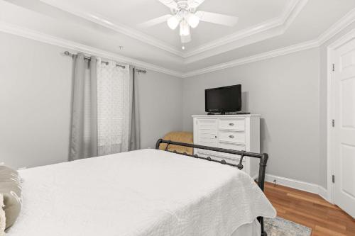 a white bedroom with a bed and a tv at Brass Rail 220 in Tybee Island
